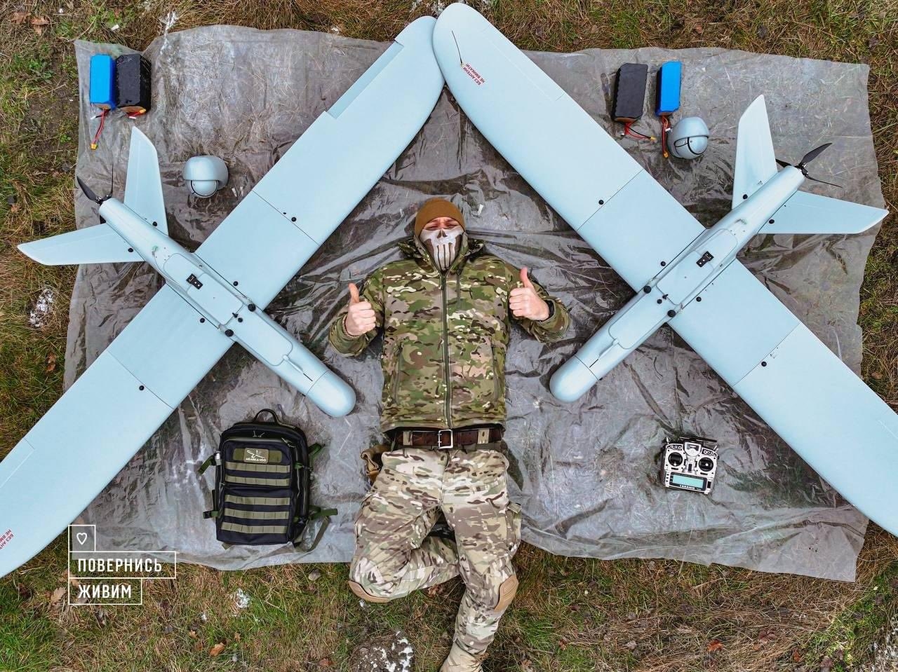 Український військовий лежить на ковдрі поміж двох безпілотників