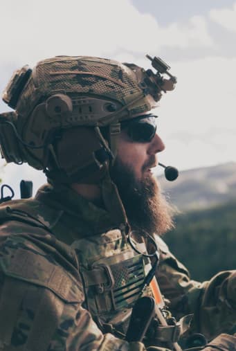 A soldier wearing ballistic glasses and a helmet with an active headset