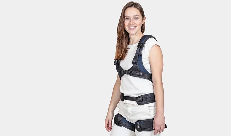 A smiling woman is standing in an exoskeleton