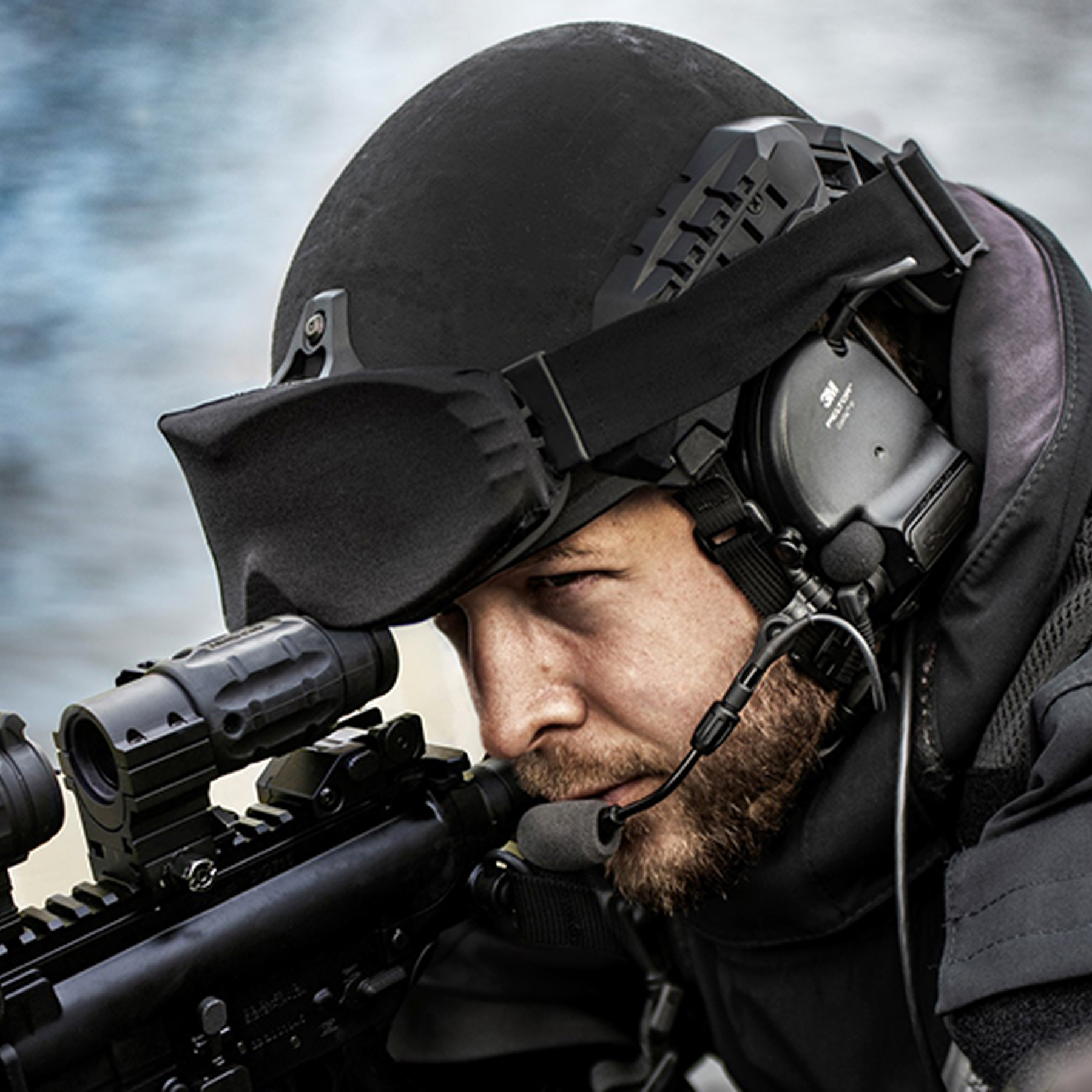 A soldier with a rifle and wearing a helmet with 3M Peltor headphones