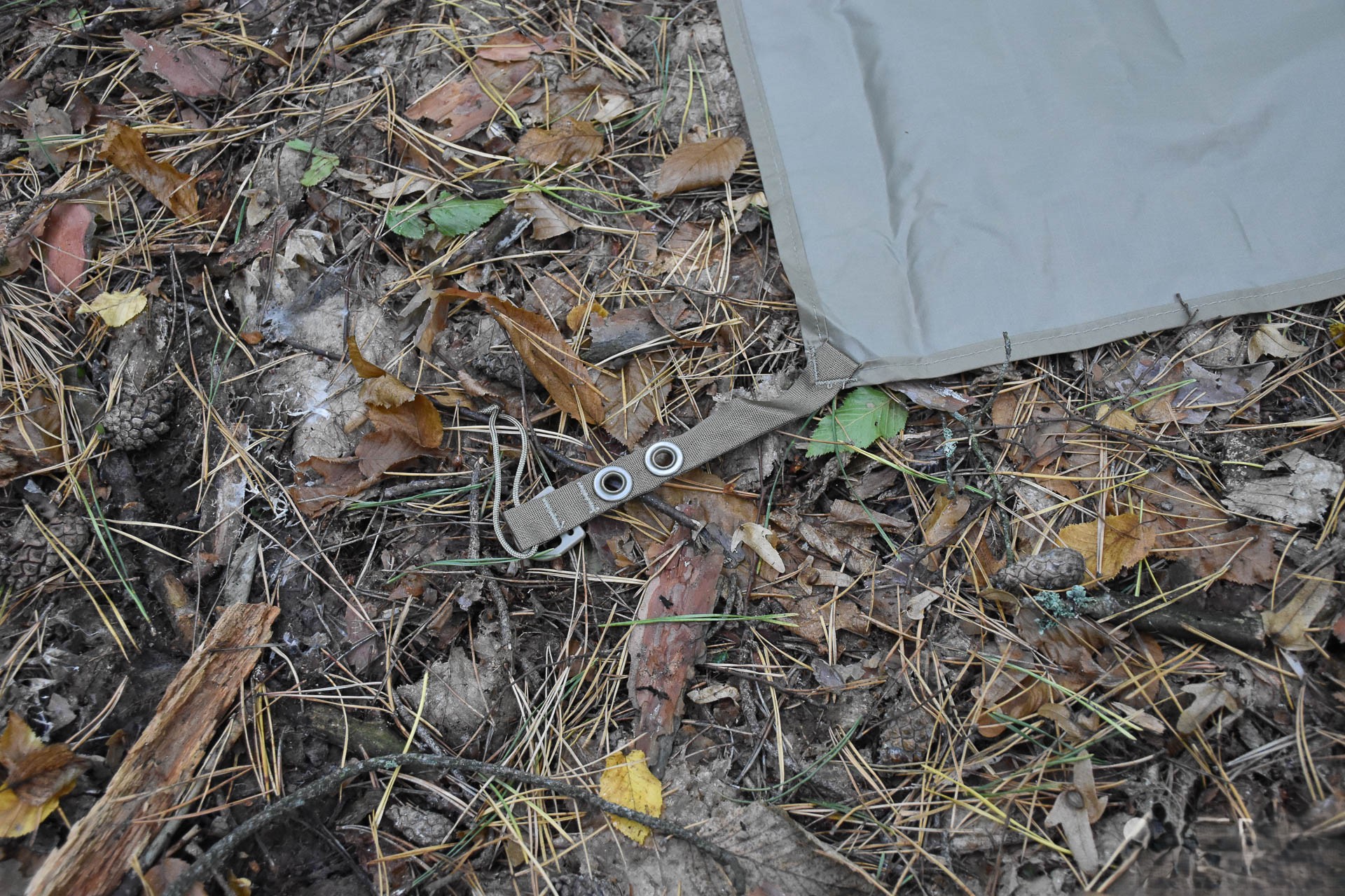 A strap with holes for pegs to secure the corner of the tent's floor