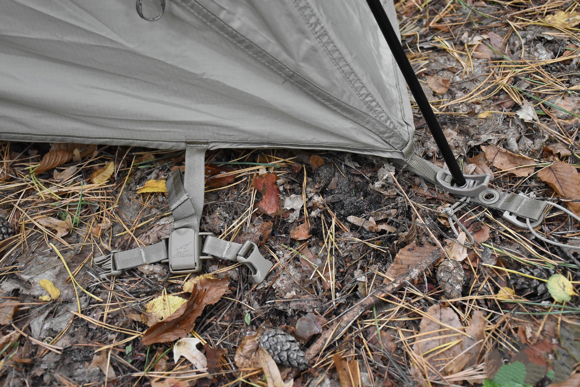 A strap with a plastic fastener for securing a tent to a camp cot