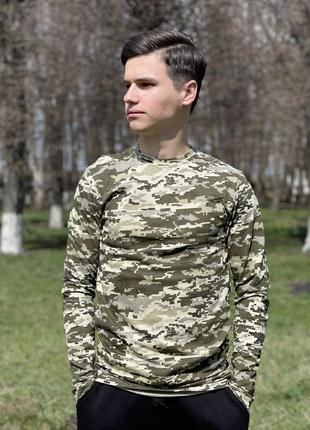 Молодий хлопець у лонгсліві камуфляжного забарвлення на тлі дерев