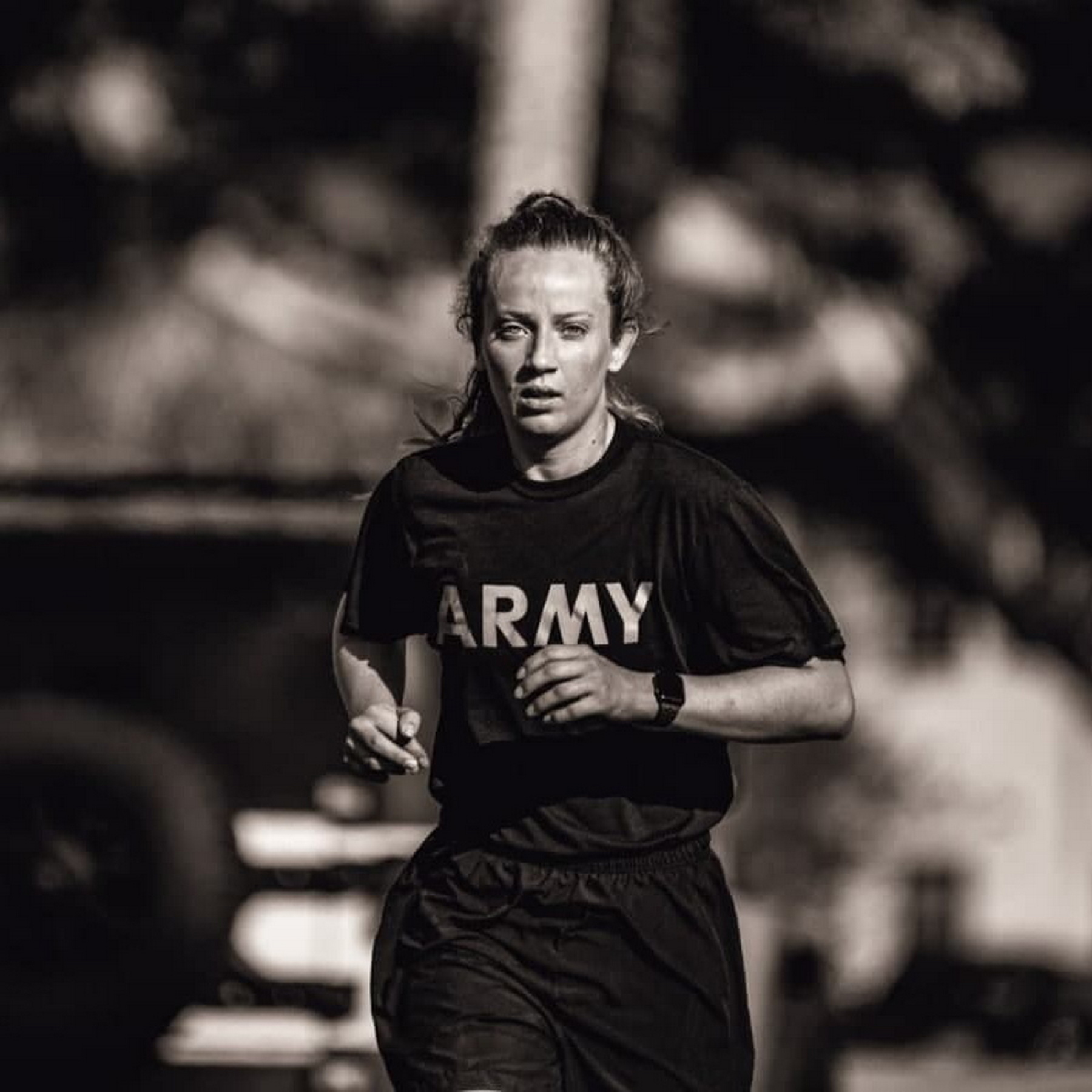 A woman is running in a black T-shirt with an ARMY print
