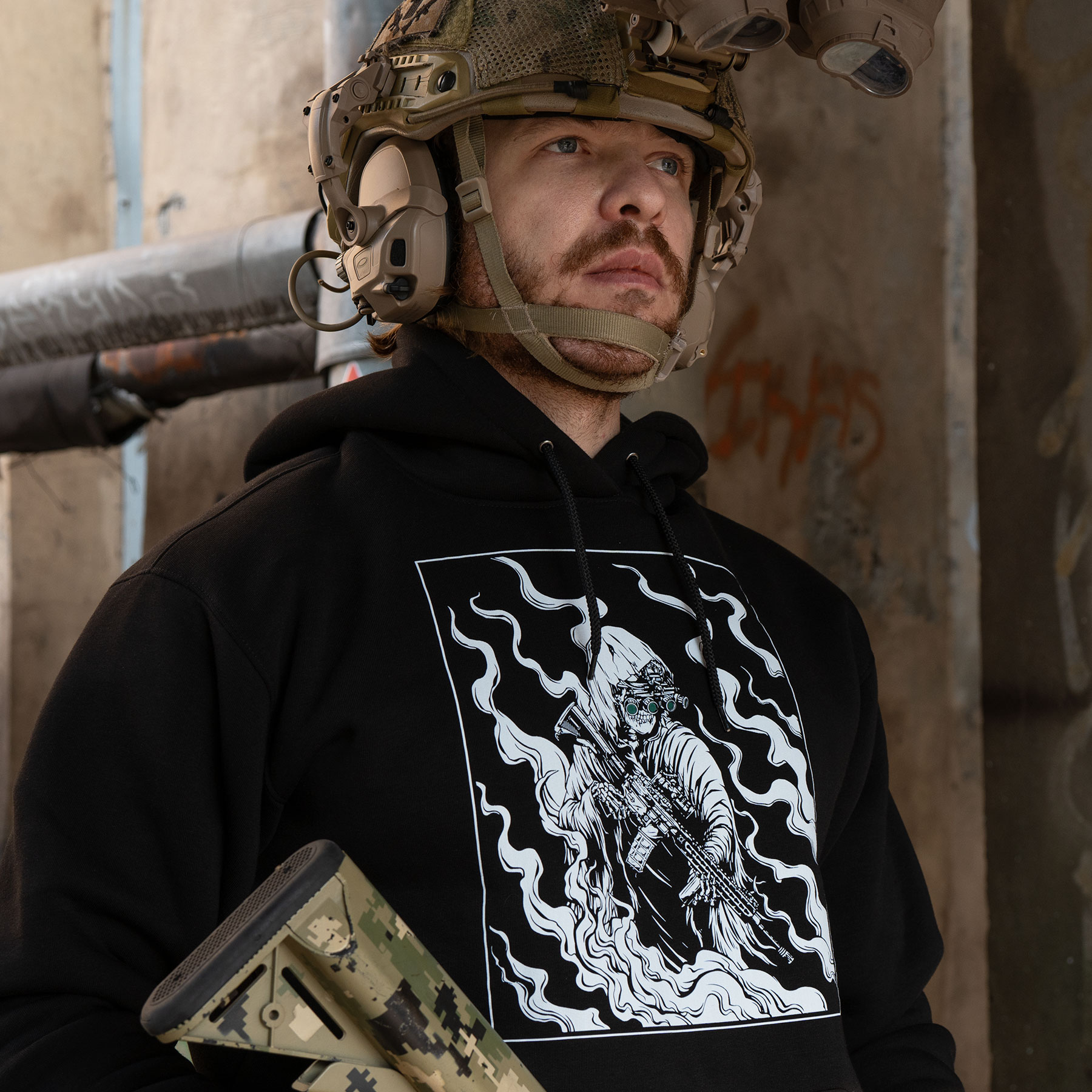 A man wearing a black hoodie with a white print of a ghost sniper