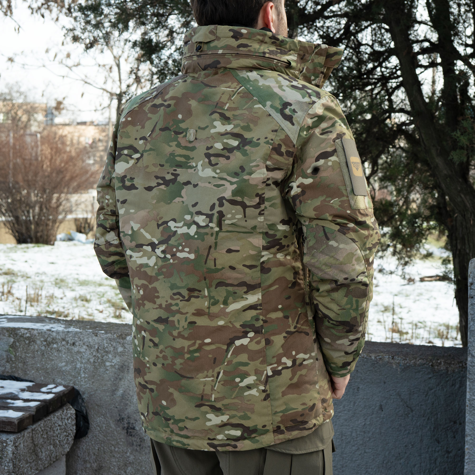 A man wearing a Multicam winter jacket (view from the back)