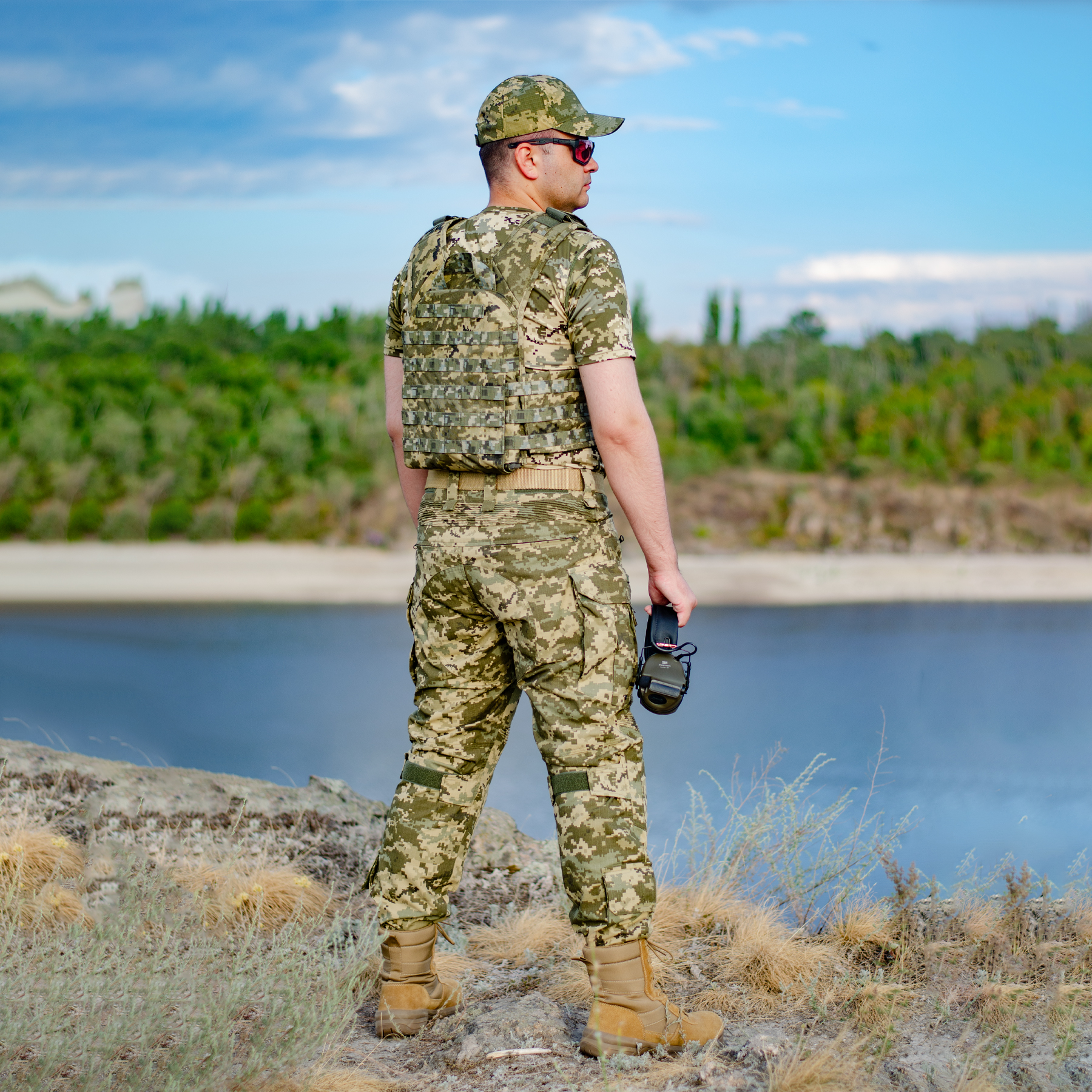 A man in pixelated gear is standing on the riverbank
