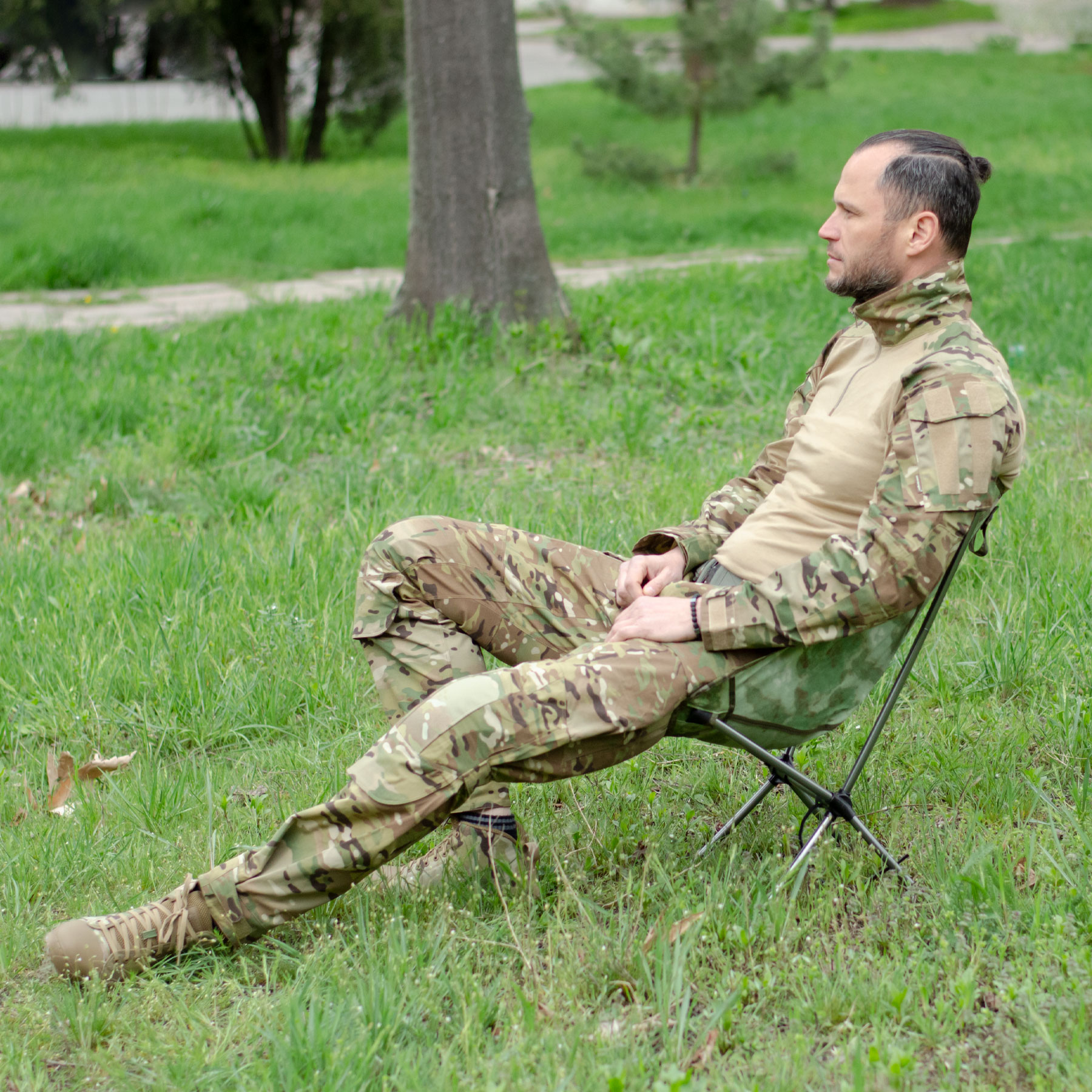 A man in a Multicam military uniform is sitting on a folding chair